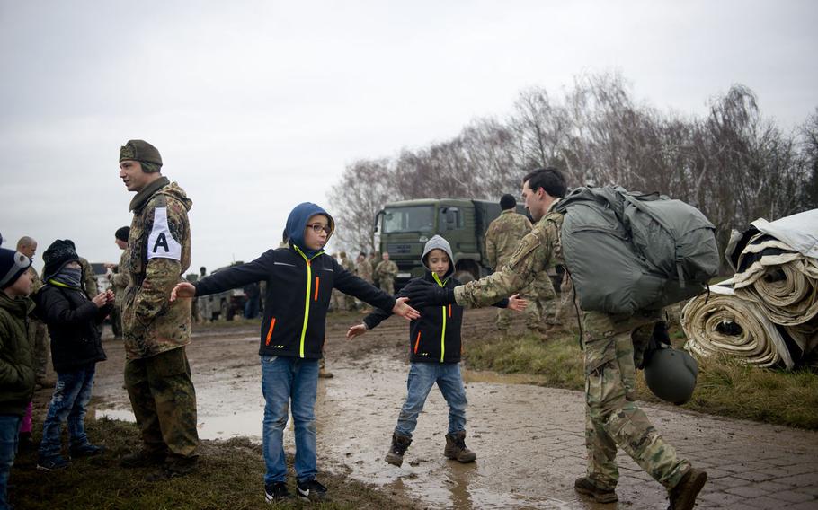 Children greet a paratrooper after a jump near Alzey, Germany, on Wednesday, Dec. 6, 2017. About 100 paratroopers from the US, Germany and the Netherlands participated in a holiday training jump to give them experience jumping with personnel from other nations and to hand out toys to local children.