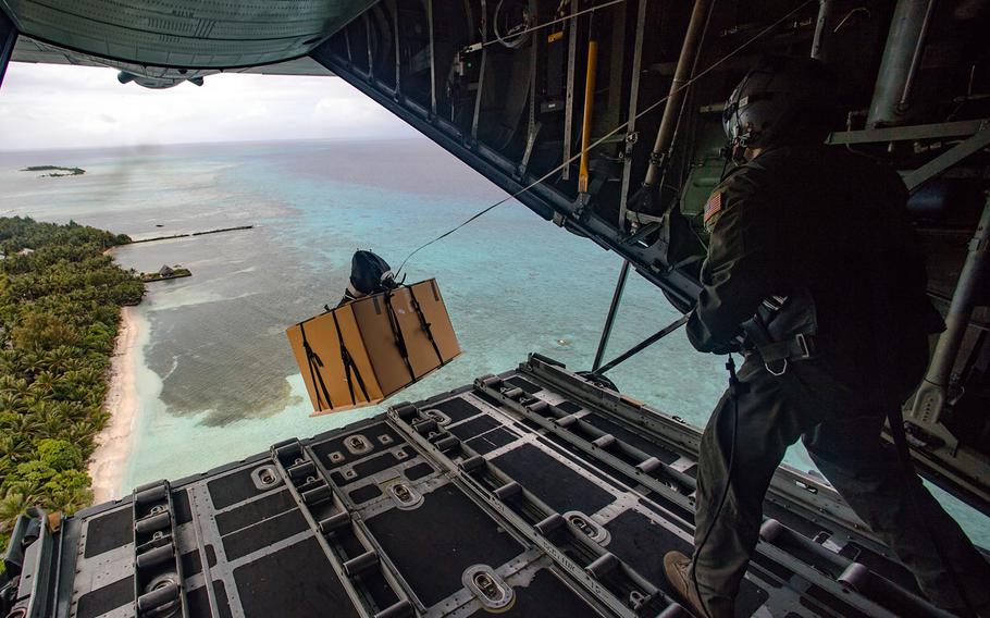 A loadmaster aboard a Japan-based C-130 cargo plane sends an Operation Christmas Drop bundle over the Federated States of Micronesia, Dec. 8, 2016.