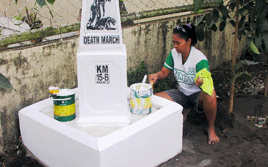 This undated photo shows Rosalie Hudson painting a Bataan Death March marker in the Philippines.