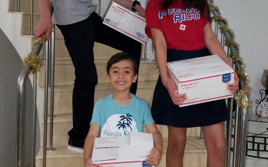 Siblings Isaac Feliciano, 13, Yadinette Feliciano, 11, and Giovanni Feliciano, 6, pose holding boxes full of aid that were later sent to hurricane victims on Puerto Rico.