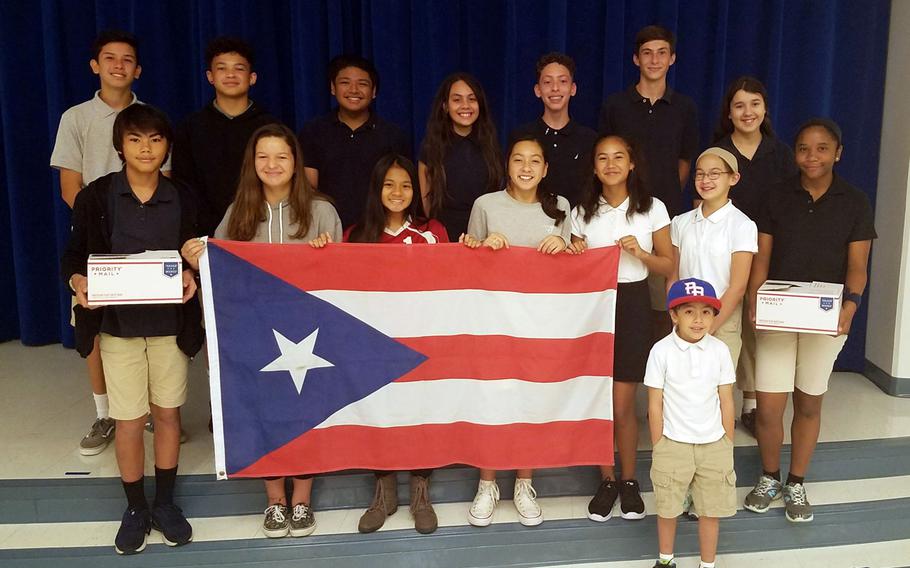 National Junior Honor Society members from Commander William C. McCool Elementary and Middle School at Naval Base Guam pose with a Puerto Rican flag after organizing a donation drive to help families affected by Hurricanes Irma and Maria.