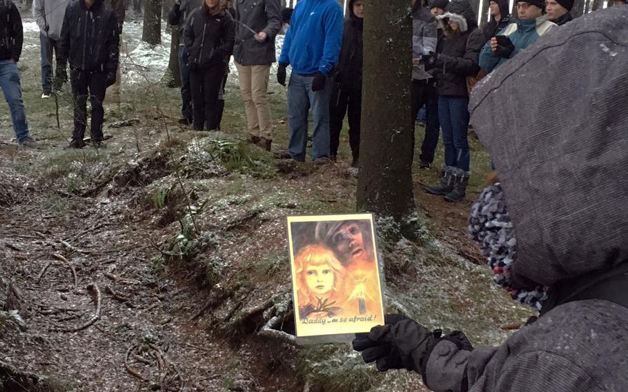 Soldiers and families from the Grafenwoehr Training Area look at German propaganda from the Battle of the Bulge while gathered around a foxhole during a trip to Bastogne, Belgium, Saturday, Dec. 16, 2017.