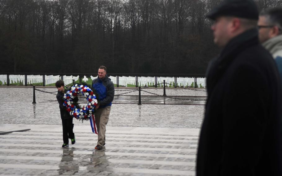 Capt. Tim Behnke, a chaplain from the Grafenwoehr Training Area, and his son Adam carry a wreath to be laid at the Luxembourg American Cemetery and Memorial, Saturday, Dec. 16, 2017.