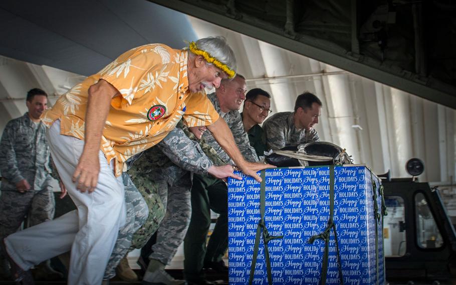 Military and civilian leaders push an Operation Christmas Drop bundle onto a C-130J Super Hercules during a ceremony at Andersen Air Force Base, Guam, Dec. 11, 2017. Operation Christmas Drop has delivered much-needed supplies to isolated islands each December since 1952.