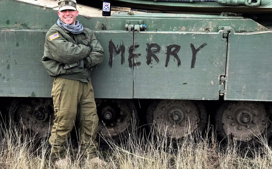 Capt. Joe Laplante, a tank commander with Company C of the 2nd Armored Brigade Combat Team, stands next to his M1A2 Abrams tank, with ''Merry'' painted on its side in mud, Thursday, Dec. 7, 2017.