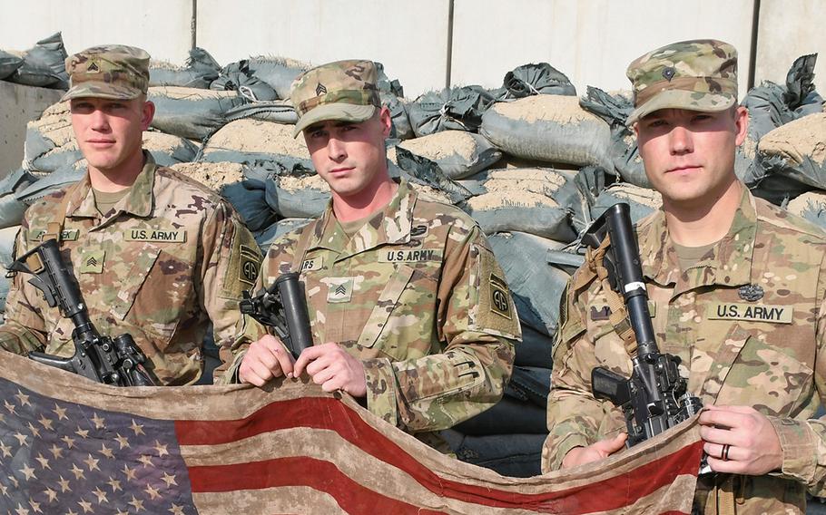 Sgt. Mark Andrisek, Sgt. Joshua Sears and Spc. Garrett ''Doc'' Young are pictured at Bagram Air Field with an American flag scarf Young's wife gave him for Christmas in 2016. He's carried it in his cargo pocket his entire time in Afghanistan, including on a Nov. 13 patrol in Kandahar province, in which a suicide car bomber wounded four of his platoon mates.