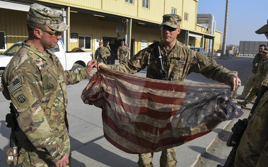 
Spc. Garrett ''Doc'' Young, pictured here at Bagram Air Field on Wednesday, Dec. 20, 2017, unfurls an American flag scarf his wife gave him for Christmas in 2016. He has carried the scarf in his cargo pocket during his time in Afghanistan, including on the patrol on Nov. 13, 2017, in which a suicide car bomber wounded four of his platoon mates.

