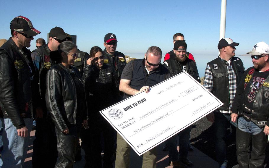 Craig Bryan, a veteran and psychologist leading the National Center for Veterans Studies, holds a check given to him Saturday, Oct. 28, by the Combat Veterans Motorcycle Association at Antelope Island State Park in Utah. The money will go toward suicide-prevention research.