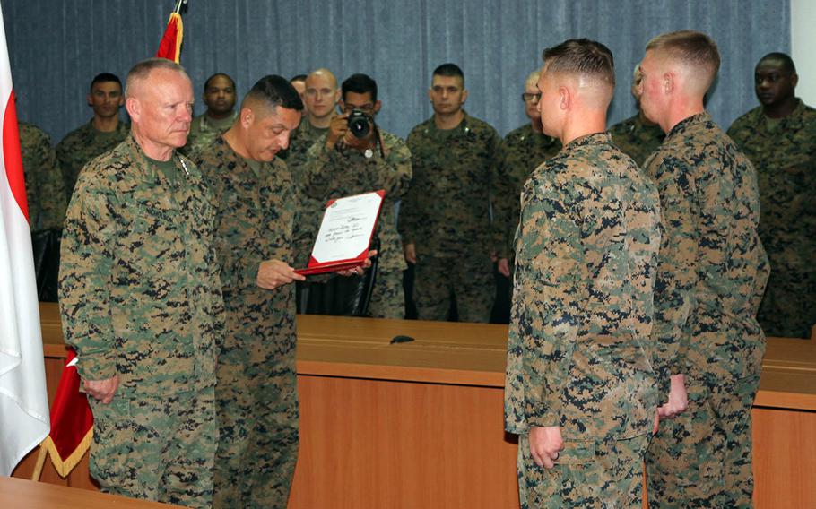 III MEF commander Lt. Gen. Lawrence Nicholson and Sgt. Maj. Mario Marquez award the Navy and Marine Corps Commendation Medal to Sgt. Justin Erler and Cpl. Matthew Dungan at Camp Courtney, Okinawa, Wednesday, Jan. 3, 2018.