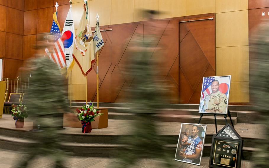 Soldiers walk by images of Staff Sgt. Kyle LeFlore at Camp Humphreys, South Korea, Thursday, Jan. 11, 2018.