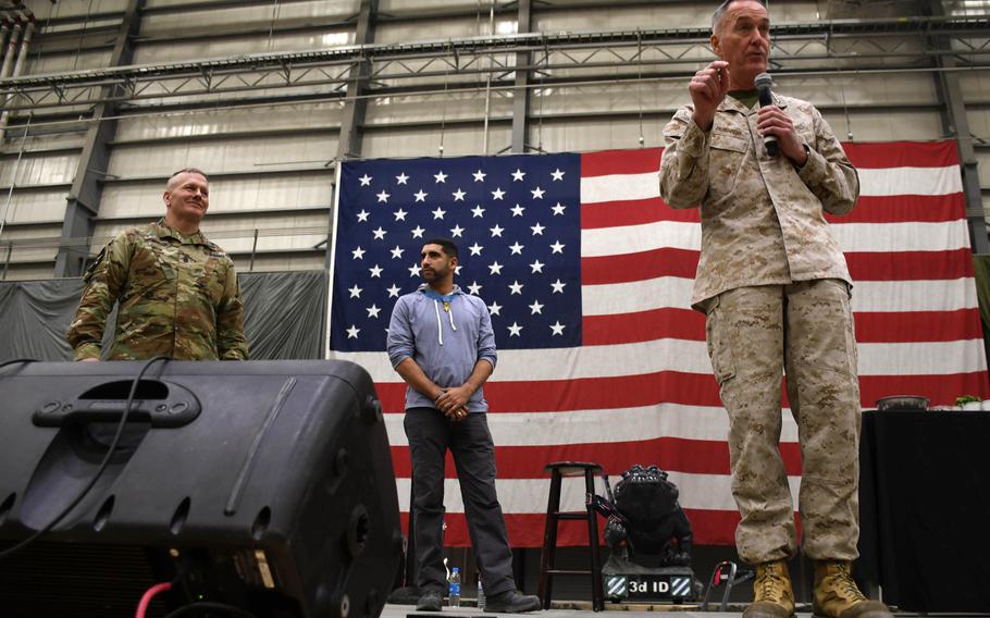Command Sgt. Maj.John Wayne Troxell, senior enlisted adviser to the chairman of the Joint Chiefs of Staff, left, listens as Gen. Joseph Dunford speaks to troops at a Christmas Eve USO show at Bagram Air Field, Afghanistan, on Sunday, Dec. 24, 2017. At center is Medal of Honor recipient Capt. Flo Groberg.
