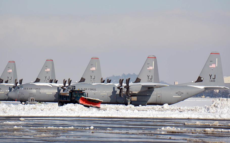 A snowplow passes C-130J Super Hercules aircraft at Yokota Air Base, Japan, Tuesday, Jan. 23, 2018.