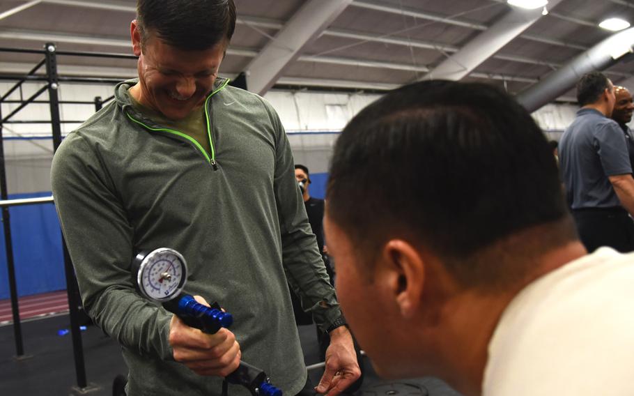 Master Sgt. Paul Foles, left, 17th Special Tactics Squadron, squeezes a dynamometer, which measures grip strength, during an occupational fitness demonstration at Joint Base Andrews, Md., Tuesday, Jan. 9, 2018.