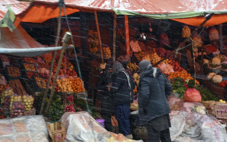Men in Kabul province, Afghanistan, shop for fruits and vegetables amid only the second winter snowfall in the country's capital and surrounding areas on Monday, Jan. 29, 2018.