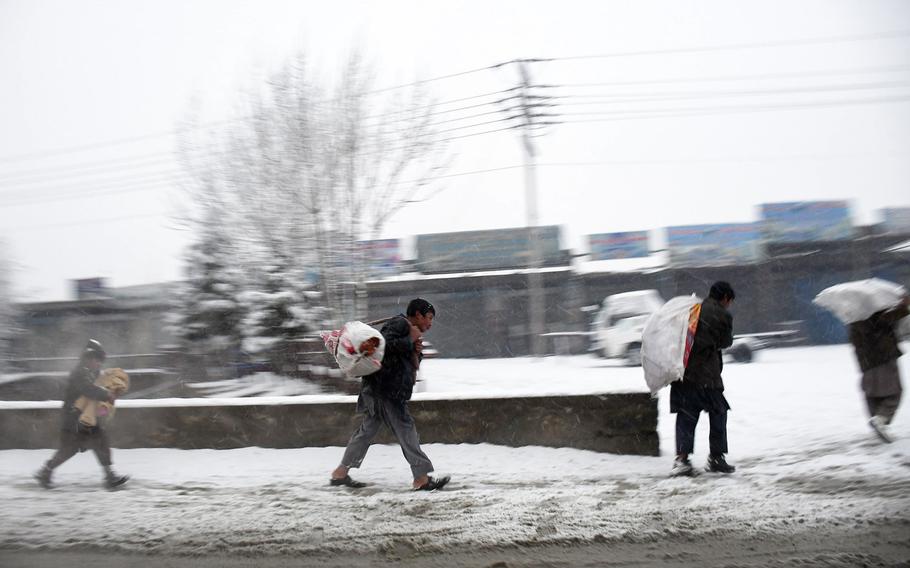 People carry goods from the market north of Kabul on a snowy day in Afghanistan on Monday, Jan. 29, 2018.