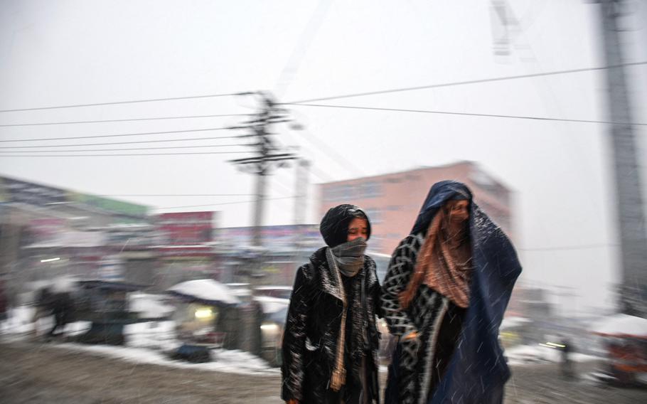 Two women, bundled up for the cold, cross a road in Kabul on Monday, Jan. 29, 2018. Snow blanketed the city for only the second time this winter after President Ashraf Ghani called on Muslims to pray for precipitation.