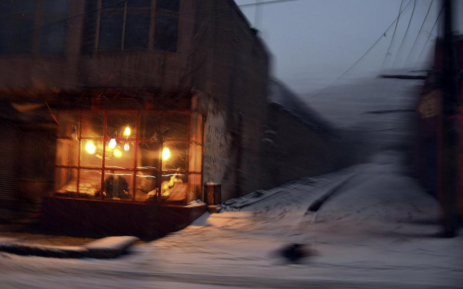 Light from a bakery fills the darkness on Monday, Jan. 29, 2018, one of the few snowy days in Kabul during the Afghan winter of 2017-2018.