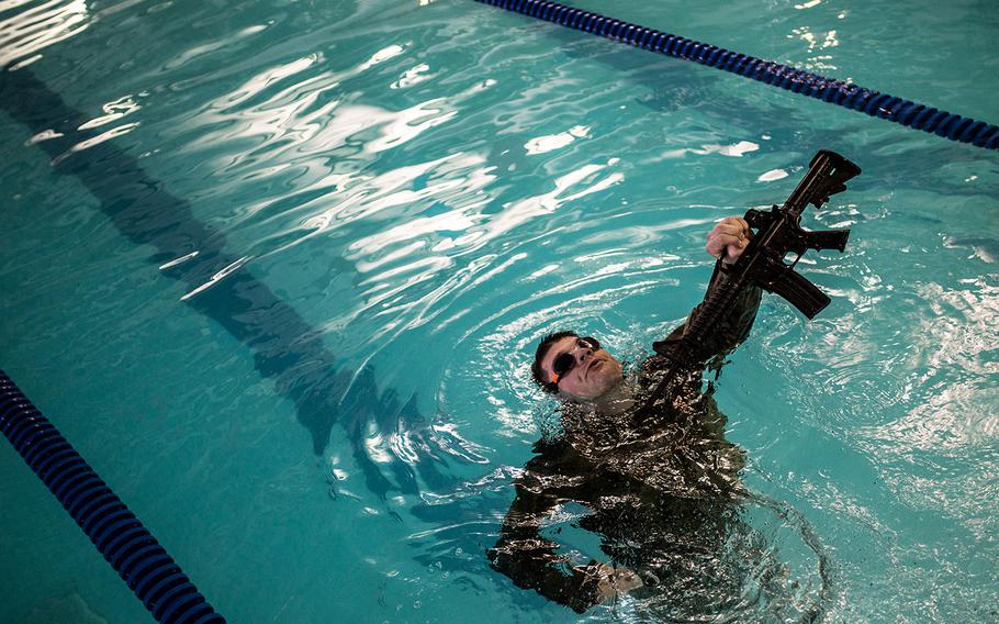 Second Lt. Adam Robinson of 55th Military Police Company, 94th Military Police Battalion treads water with his rifle during the 19th Expeditionary Command best-warrior competition, Monday, March 5, 2018.