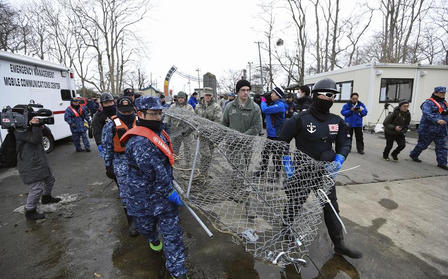 U.S. and Japanese servicemembers work together to clean up Lake Ogawara near Misawa Air Base, Japan, earlier this month after an F-16 jettisoned its fuel tanks because of an emergency.