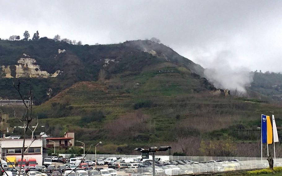 A Campi Flegrei crater blows steam from a hillside above a car lot on Friday, March 16, 2018 in Pozzuoli, Italy. The supervolcano has become more unpredictable and could threaten U.S. military installations in Naples if it erupts. 