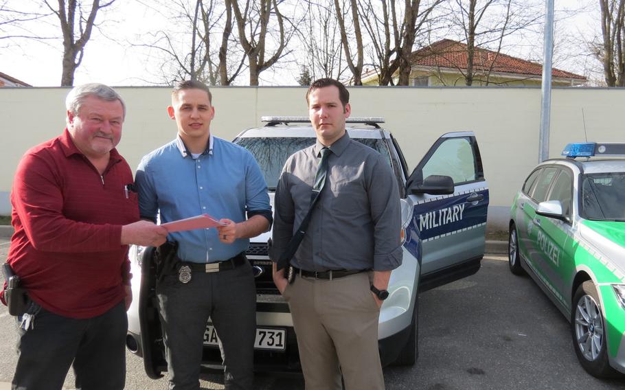 Investigator Andreas Mueller, left, of the Auerbach Police Department, gives a list of recovered items to Vilseck military police officers Sebastian Rupp, center, and Michael Thompson, right.