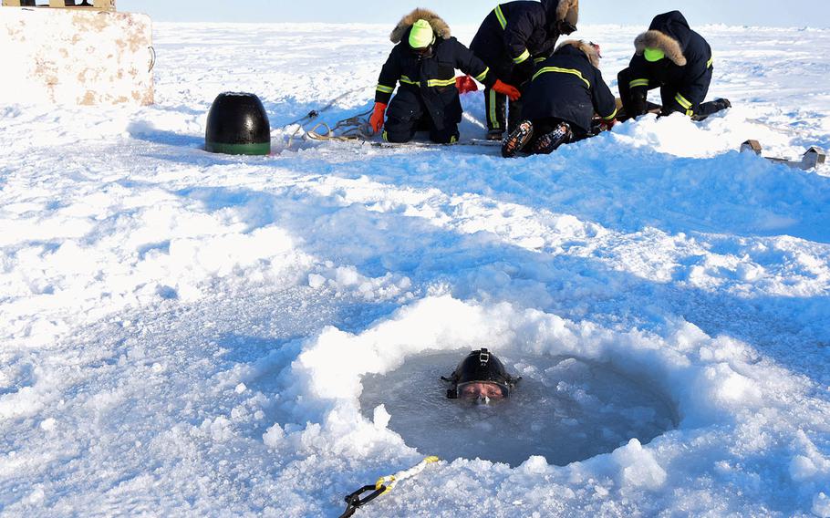 A diver assigned to Underwater Construction Team 1 surfaces from an Arctic ice hole March 16, 2018, during a torpedo exercise in support of Ice Exercise 2018.