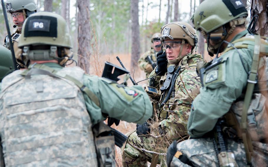 A soldier with the 1st Security Force Assistance Brigade, center, listens to a radio as he huddles with role players portraying Afghan soldiers during a training patrol Jan. 16 at the Joint Readiness Training Center at Fort Polk in Louisiana. The 1st SFAB was preparing for its spring deployment to Afghanistan, where it will train and advise security forces near the front lines. 