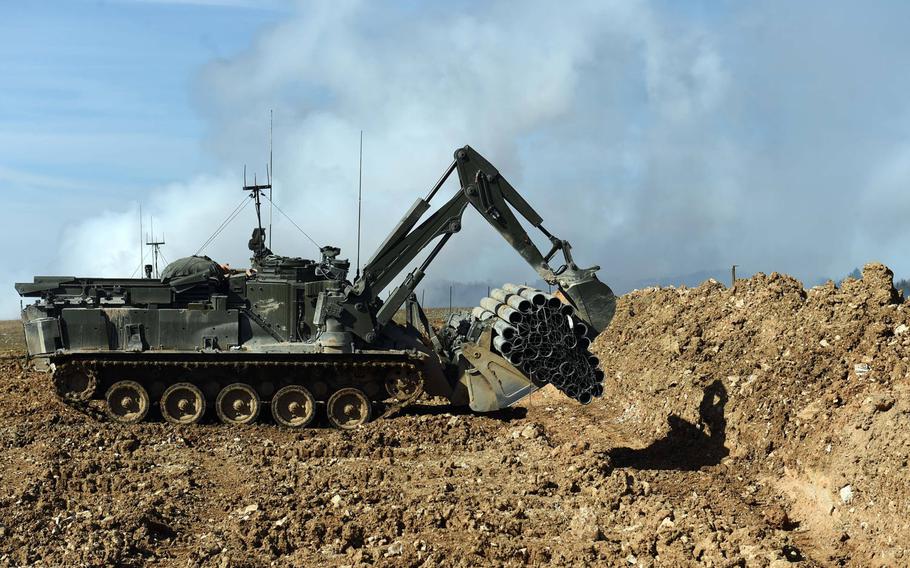 An unmanned U.K. Terrier engineering vehicle drops a fascine bundle into a tank trench during the Robotic Complex Breach Concept demonstration at Grafenwoehr, Germany, Friday, April 6, 2018.