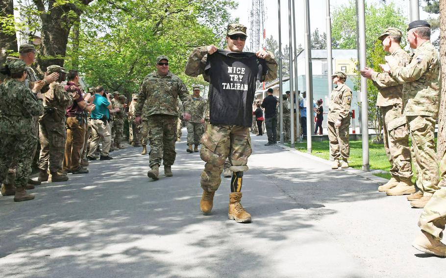 Retired Army Spc. Justin Lane arrives at an operation Proper Exit event at NATO's Resolute Support Headquarters in Kabul, Afghanistan, on Saturday, April 7, 2018, holding a shirt that reads, "Nice Try Taliban." Lane lost both legs in combat in 2011. 
