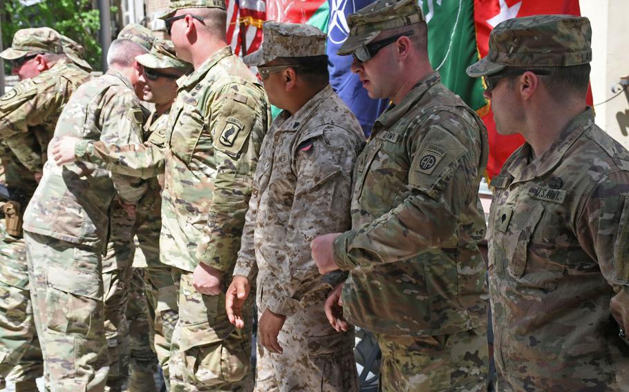 Retired Army Spc. Justin Lane, right, Army Sgt. Jonathan Harmon, retired Marine Corps Sgt. Hubert Gonzalez and retired Army Sgt. Franz Walkup watch as Army Gen. John Nicholson, the top U.S. commander in Afghanistan, greets retired Army Staff Sgt. Jaymes Poling during an Operation Proper Exit ceremony in Kabul on Saturday, April 7, 2018. 
