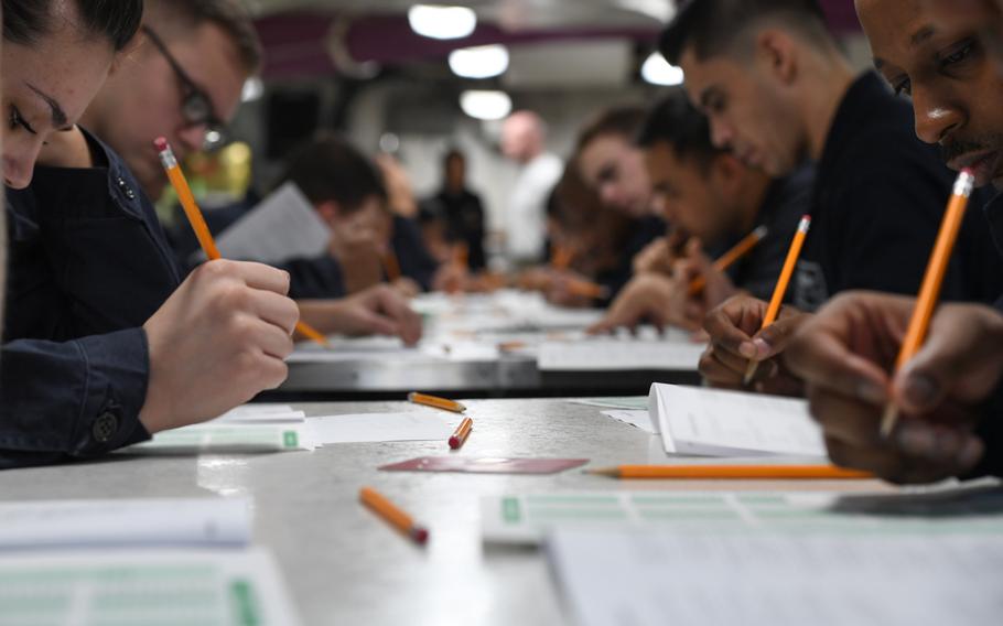 Sailors take the E-6 advancement exam aboard the aircraft carrier USS Theodore Roosevelt in the Arabian Gulf, March 1, 2018. Note: photo has been edited for security purposes by blurring test pages.