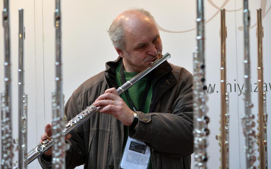 Framed by flutes, a visitor to the Musikmesse in Frankfurt, Germany, tries a Japanese model by Miyazawa , Wednesday, April 11, 2018.