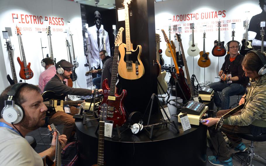Visitors to the Musikmesse in Frankfurt, Germany, try out guitars at the Yamaha stand, Wednesday, April 11, 2018.