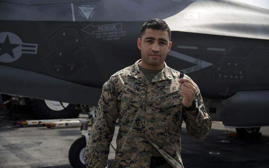 Chief Warrant Officer 2 Daniel Rodriguez holds a 3-D printed plastic bumper for an F-35B Lightning II landing gear door aboard the USS Wasp, April 19, 2018.