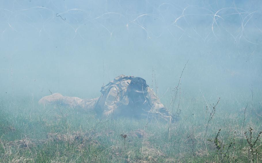 A soldier with the 1st Infantry Division's 2nd Armored Brigade Combat Team puts on his gas mask as a cloud of tear gas envelops him, during an exercise at Grafenwoehr, Germany, Thursday, April 19, 2018.