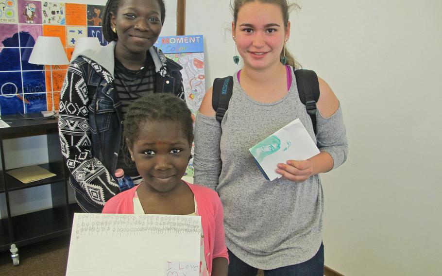 Fatima Sylla, front, holds the pictures she drew at a recent weekly free art session at the Vicenza library. Her sister, Lika Fatima, left, and Maria Contreras also attended the session.