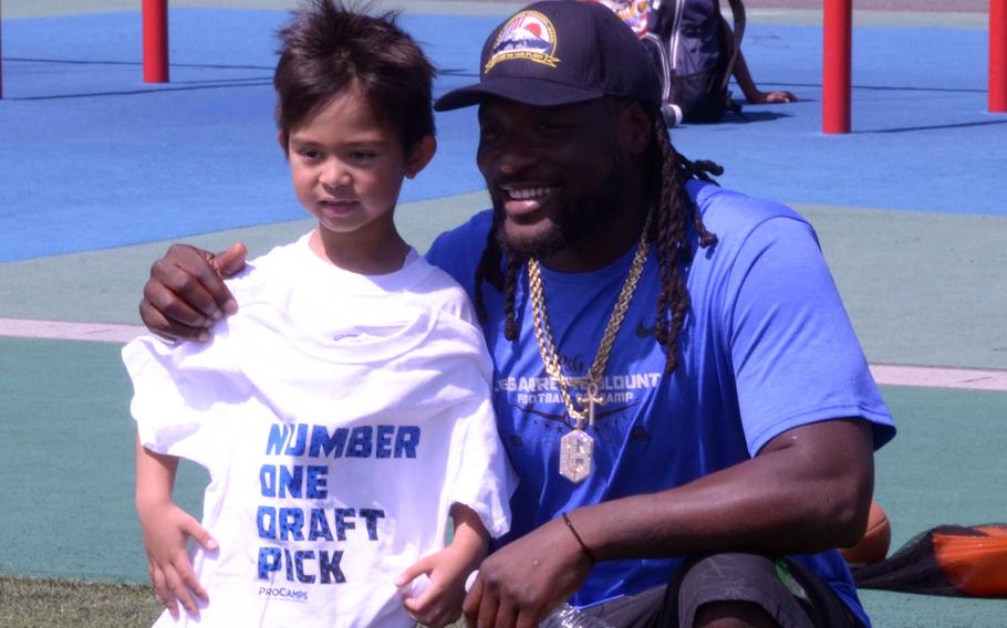 Detroit Lions running back LeGarrette Blount poses with a child during a football camp at Yokosuka Naval Base, Japan, Saturday, April 28, 2018.