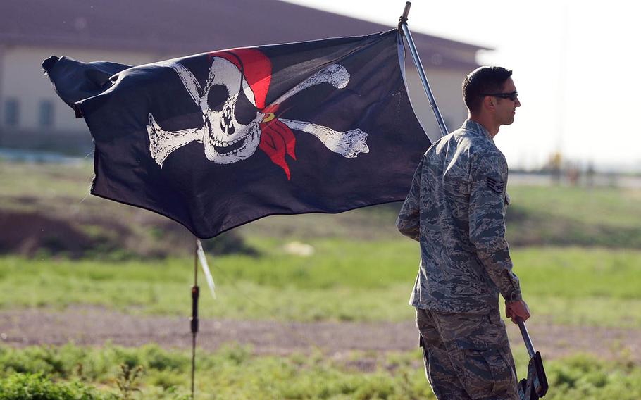 An Air Force staff sergeant carries a Jolly Roger flag to an AC-130H Spectre gunship at Cannon Air Force Base, N.M., in 2015.