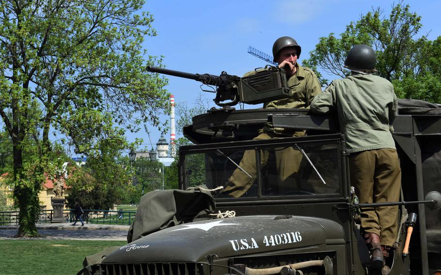 Czech re-enactors, dressed as World War II GIs, talk with each other against the background of the brewery in Pilsen, Czech Republic, Friday, May 4, 2018. The city, which gave the famous beer its name, was commemorating liberation from Nazi occupation.