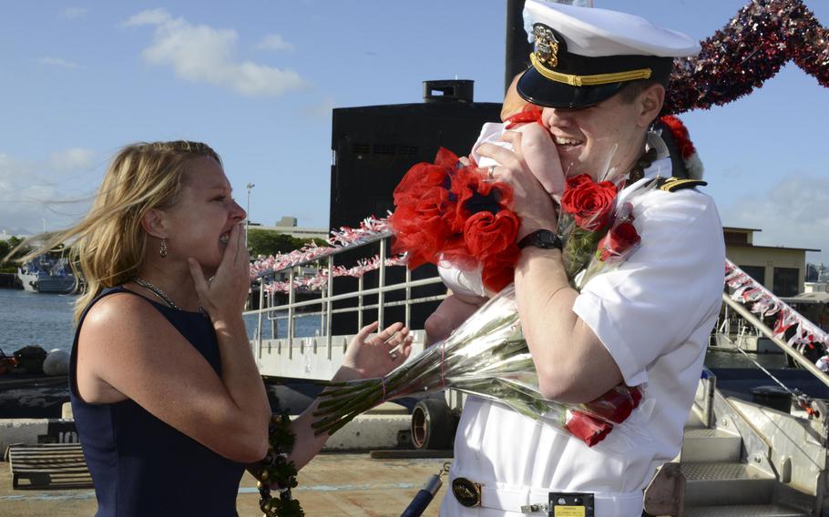 Lt. Dave Steinberger, communications officer aboard the Los Angeles-class fatal attack submarine USS Columbia, is welcomed home by his wife and their new baby daughter at the submarine piers of Joint Base Pearl Harbor-Hickam after a deployment to the western Pacific region. The Navy announced a new parental leave plan on Thursday.