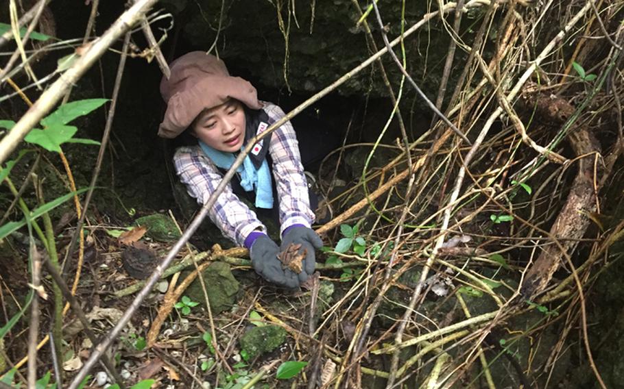 Kuentai-USA secretary general Yukari Akatsuka emerges from a cave in the Okinawan jungle May 9, 2018 carrying unknown human remains and artifacts left over from the Battle of Okinawa.