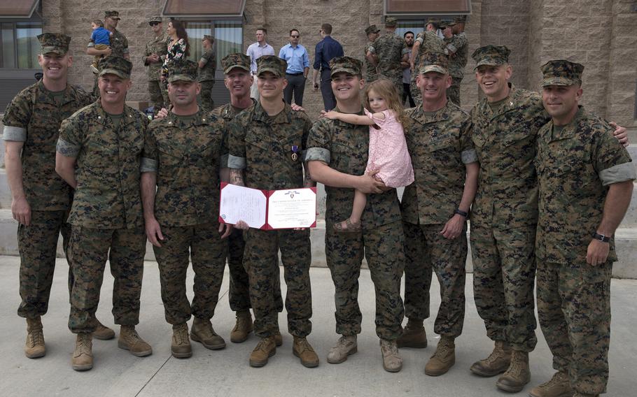 U.S. Marine Corps Sgt. Cameron T. Halkovich, center, a combat engineer with 1st Combat Engineer Battalion, 1st Marine Division, poses for a group photo after being awarded the Purple Heart for wounds received in action on Feb. 17, 2018, in support of Operation Inherent Resolve. Cpl. Kane Downey is on the right holding his daughter.