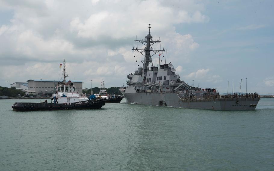 Tugboats assist the USS John S. McCain as it steers toward Changi Naval Base, Singapore, following a collision, Aug. 21, 2017.