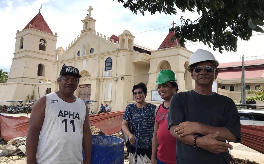 Many residents of Balangiga, Philippines, say they welcome the upcoming return of church bells taken by American troops in 1902. Local government official Sanny Elacion, left, and historian Alicia Valdenor, second from left, pose with construction workers near the rebuilt church, Sept. 20, 2018.