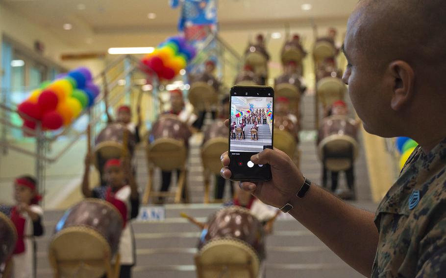 A Marine takes video of a taiko drumming performance by Zukeran Elementary students during a ribbon-cutting ceremony for the new school at Camp Foster, Okinawa, Wednesday, Oct. 10, 2018.