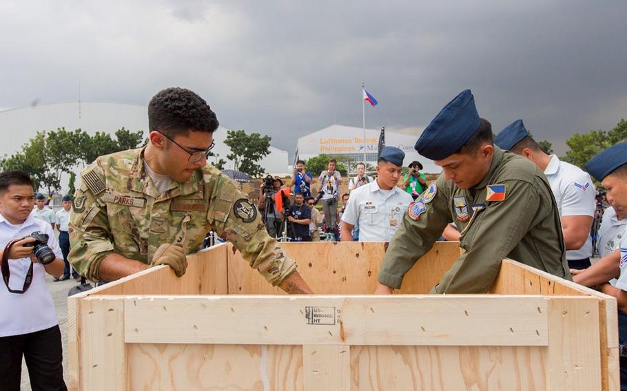 U.S. And Philippine airmen open the crates of the Balangiga Bells before a ceremony honoring the bells' return at Villamor Air Base, Manila, Philippines, Tuesday, Dec. 11, 2018.