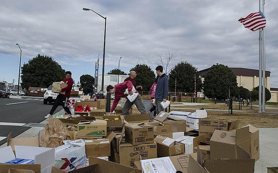 Volunteers and students sort donations bound for orphans outside Yokota High School at Yokota Air Base, Japan, Thursday Dec. 13, 2018.
