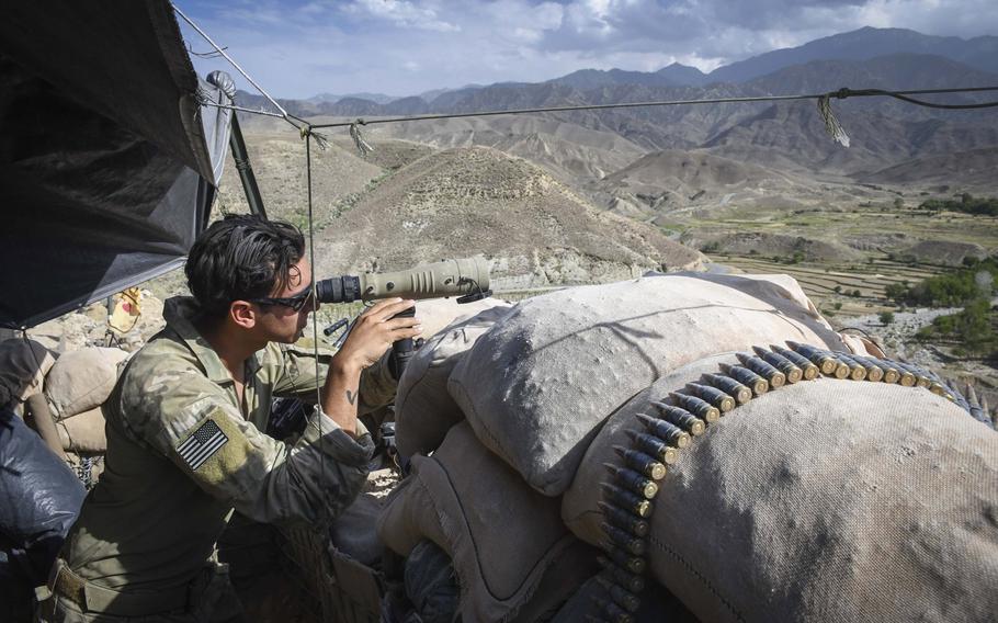 A Special Forces soldier peers through a scope while manning Observation Post Krakken, a checkpoint overlooking a key valley in Deh Bala district in Nangarhar province in July.  