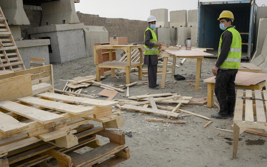 Carpenters in the village outside of Bagram Air Field pick through wood pallets recycled from the base to find the ones most suited to build tables, chairs and birdhouses.