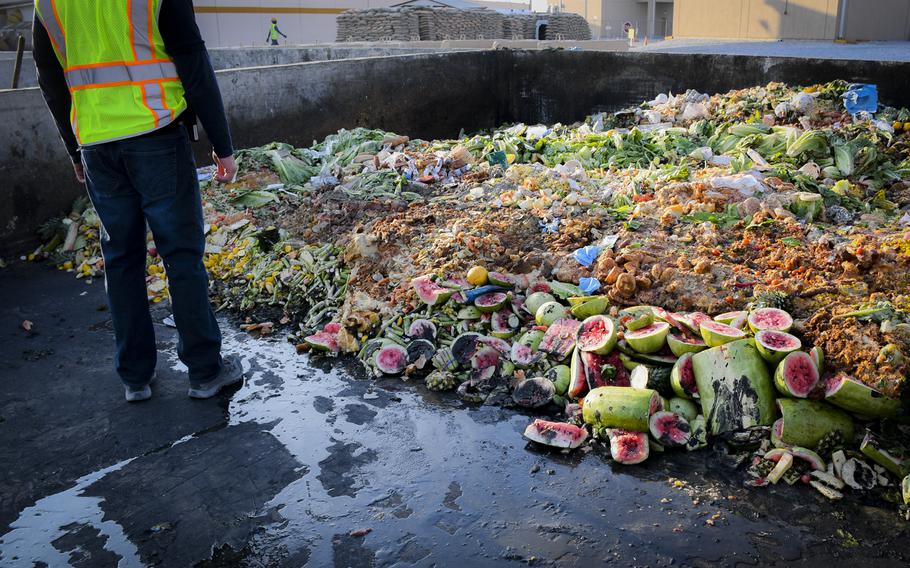 A sanitation worker at Bagram Air Field looks over some of the tons of food waste produced each day at the base. Workers collect food waste from the base cafeterias in barrels and prepare them for composting. The compost is used to grow vegetables sold at upscale grocery stores in Kabul.